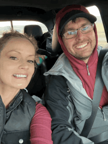 a man and a woman are sitting in the back seat of a car