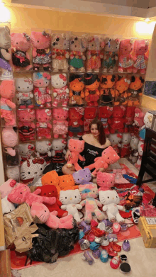 a woman is surrounded by stuffed hello kitty toys