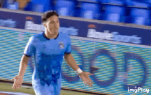 a man in a blue soccer jersey is standing on a field .