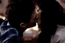 a man and a woman are kissing in front of a dark background .