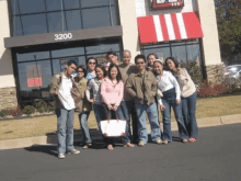 a group of people are posing for a picture in front of a kfc restaurant