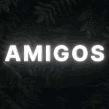 the word amigos is lit up in white on a black background