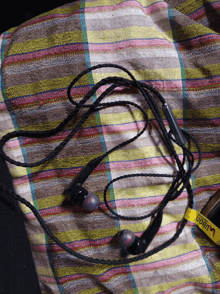 a pair of ear buds laying on a striped cloth with a yellow tag that says ' ear buds '