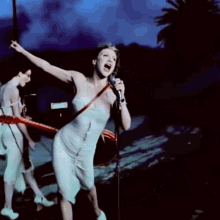 a woman in a white dress singing into a microphone with a sign in the background that says ' california '