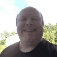 a man is smiling for the camera while wearing a black t-shirt .