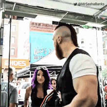 a man with a mohawk and a woman with purple hair are standing next to each other in front of a shoe store .