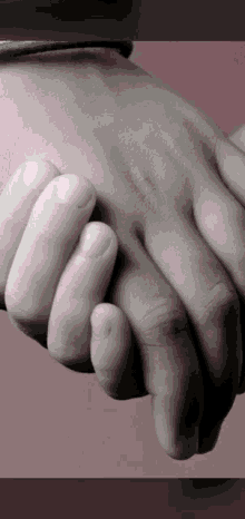 a black and white photo of two hands holding each other