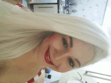 a woman with long white hair and red lips smiles for the camera