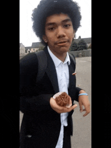 a young man in a suit is holding a doughnut in his hand