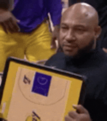 a bald man is holding a framed picture of a basketball player .