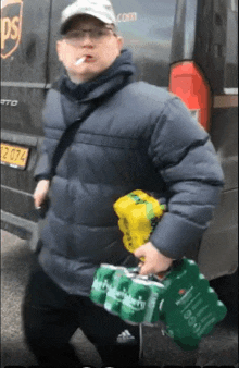 a man is smoking a cigarette while carrying a stack of beer cans