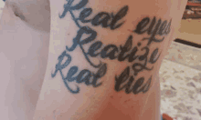 a close up of a person 's arm with a tattoo that says real eyes realize real lies