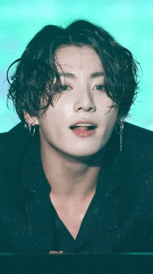 a close up of a young man with curly hair and earrings