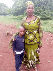 a woman in a green dress is standing next to a boy in a blue shirt .