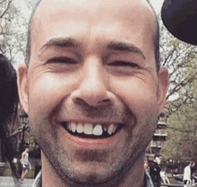 a close up of a man 's face smiling with a mickey mouse hat in the background