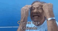 an elderly man is crying with his hands on his head and the words que no virga entiende are written above him .