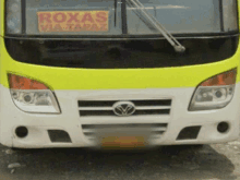 a yellow and white bus with roxas via tapaz written on the front