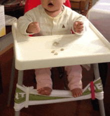 a baby is sitting in a high chair with a white tray on top of it