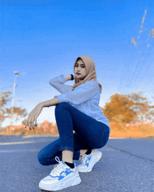 a woman wearing a hijab is squatting on the ground