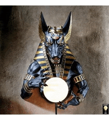 a statue of anubis is holding a ball in his hands and looking at it .