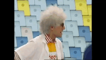 a man in a white lab coat and sunglasses is standing in front of a wall of colorful squares .