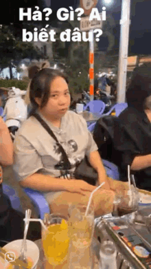 a woman is sitting at a table with a glass of orange juice and a straw in her mouth .