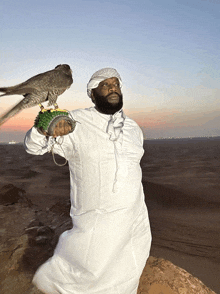 a man in a white robe holds a falcon on his shoulder