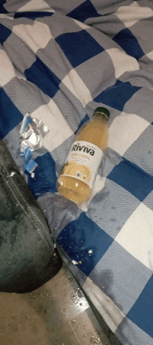 a bottle of riviva sits on a blue and white checkered bedspread