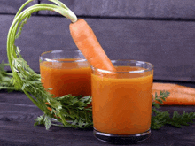 two glasses of carrot juice with a carrot sticking out of it