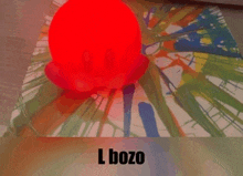 a red ball is sitting on top of a colorful table cloth with the words l bozo on the bottom .