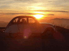 a car is parked in front of a sunset