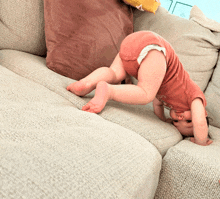 a baby is doing a handstand on a couch with a shirt that says ' i love you ' on it