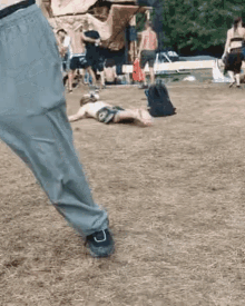 a man is laying on the ground in the grass at a festival while a woman stands in the background .