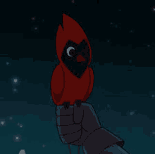 a person is holding a small red bird with a black head on their hand .