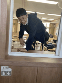 a boy cleaning a desk in a classroom with a fire extinguisher sticker on the wall