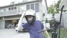 a man wearing a helmet in front of a house with a license plate that starts with the letter s