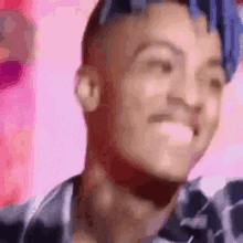 a man with blue hair is smiling and making a funny face .