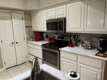 a kitchen with white cabinets and stainless steel appliances including a coffee maker