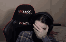 a person covering their face in front of a xmax pro chair