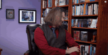 a man in a red shirt is sitting in front of a bookshelf that has a book titled " magic " in it