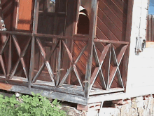 a porch with a wooden railing and a broken glass door