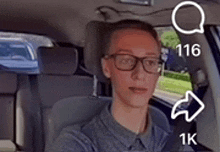 a man with glasses is sitting in the back seat of a car .