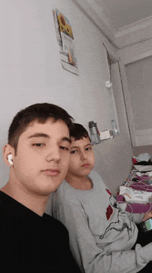 two boys are posing for a picture in front of a wall that has a picture of a sunflower on it