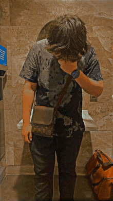 a man wearing a louis vuitton bag stands in a bathroom