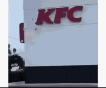 a kfc sign is on the side of a white building