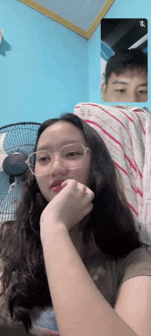 a girl wearing glasses is talking to a boy on a video call .