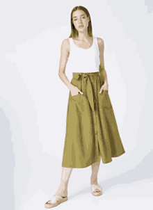 a woman in a white tank top and green skirt