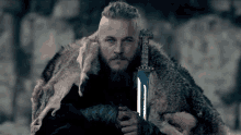 a man with a beard and blue eyes holds a sword