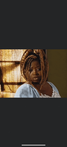 a woman with braids in her hair is wearing a blue top