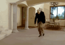 a man in a black shirt is dancing in a room with columns